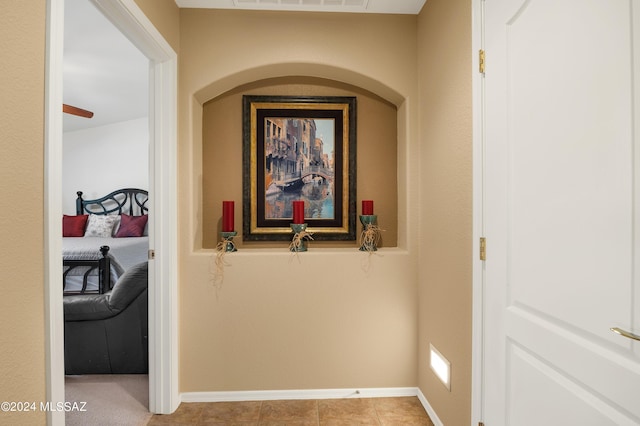 hallway with visible vents, baseboards, and light tile patterned floors