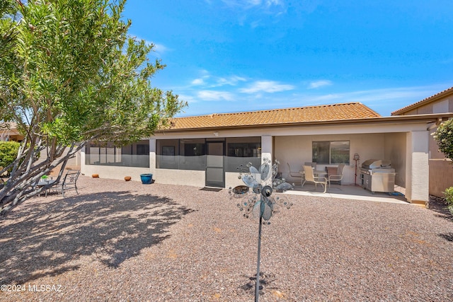 back of property featuring a patio area, a tile roof, and a sunroom