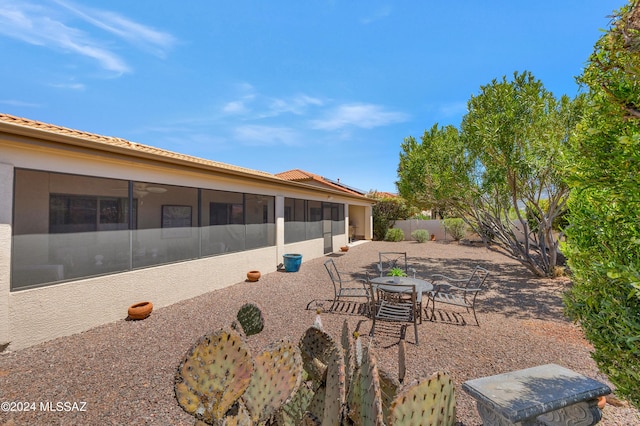 view of yard with a sunroom, a patio area, fence, and outdoor dining area