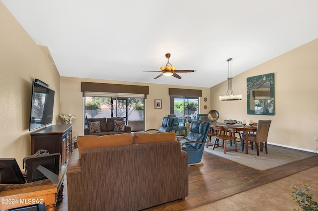 living area with baseboards, vaulted ceiling, wood finished floors, and ceiling fan with notable chandelier