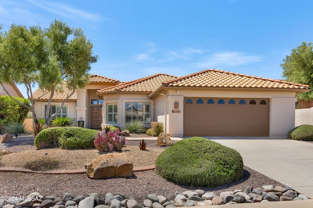 mediterranean / spanish-style house featuring an attached garage, driveway, a tiled roof, and stucco siding