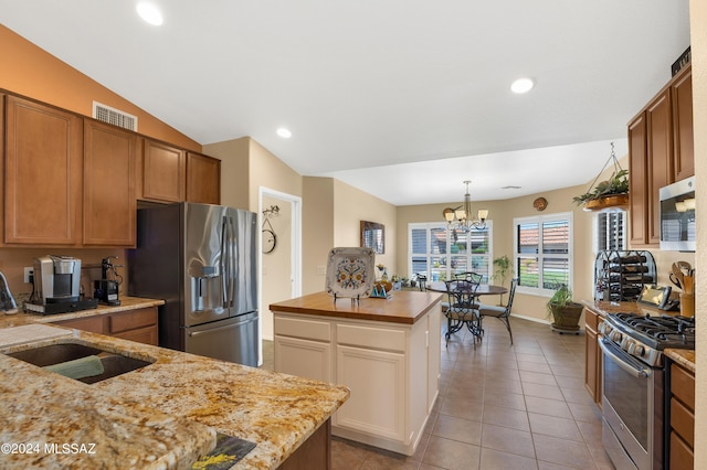 kitchen featuring visible vents, lofted ceiling, a center island, stainless steel appliances, and a sink