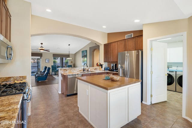 kitchen with pendant lighting, light countertops, appliances with stainless steel finishes, a kitchen island, and separate washer and dryer