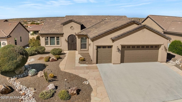 view of front of property featuring concrete driveway, an attached garage, a tiled roof, and stucco siding