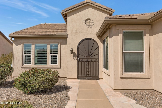 doorway to property featuring a tile roof and stucco siding