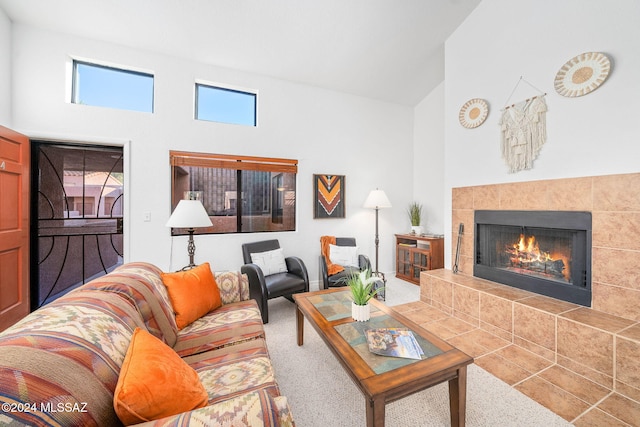 living room with a tiled fireplace, carpet floors, and high vaulted ceiling