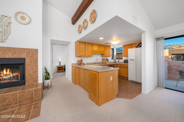 kitchen featuring a tiled fireplace, light colored carpet, kitchen peninsula, and white fridge with ice dispenser