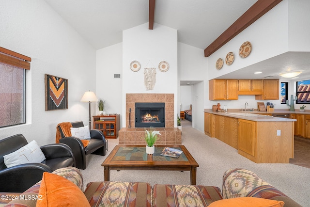 living room featuring sink, a tile fireplace, beam ceiling, high vaulted ceiling, and light colored carpet