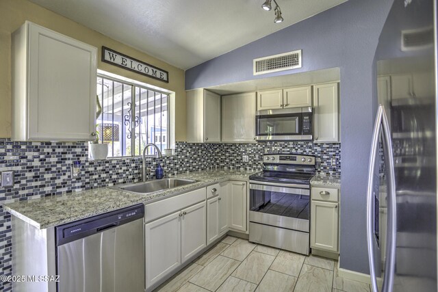 kitchen with visible vents, lofted ceiling, a sink, decorative backsplash, and stainless steel appliances