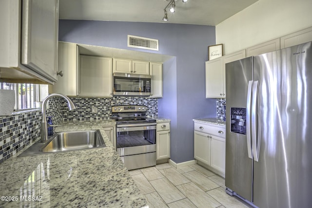 kitchen featuring tasteful backsplash, visible vents, vaulted ceiling, appliances with stainless steel finishes, and a sink