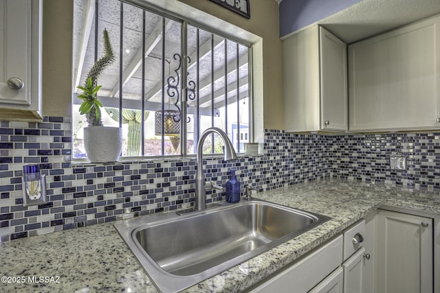 kitchen with white cabinets, tasteful backsplash, and a sink