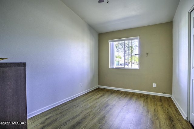 spare room featuring ceiling fan, baseboards, and wood finished floors