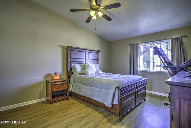 bedroom featuring lofted ceiling, wood finished floors, baseboards, and ceiling fan