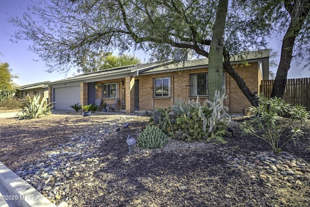 single story home with brick siding, a garage, and fence