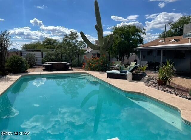 pool with a patio area, fence, and a hot tub