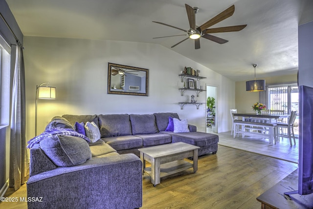 living area with ceiling fan, lofted ceiling, and wood finished floors