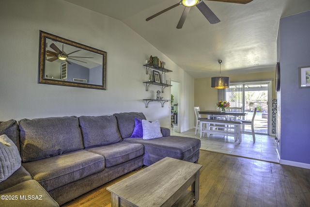 living area with baseboards, wood-type flooring, lofted ceiling, and ceiling fan