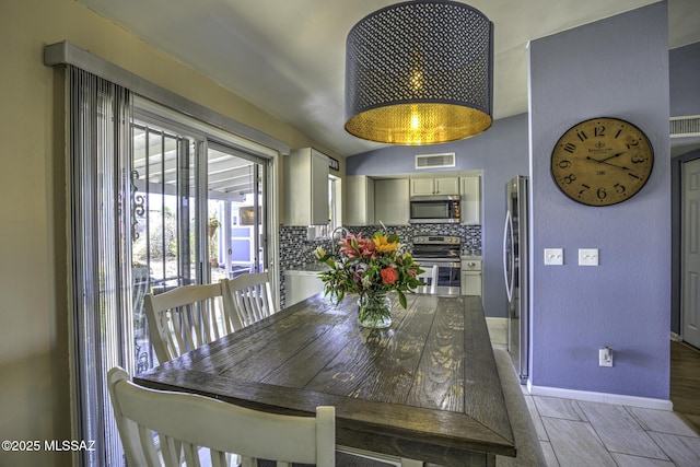 dining room featuring visible vents, lofted ceiling, and baseboards