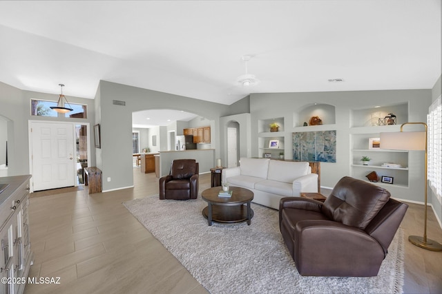 living room with built in shelves, light hardwood / wood-style floors, and vaulted ceiling