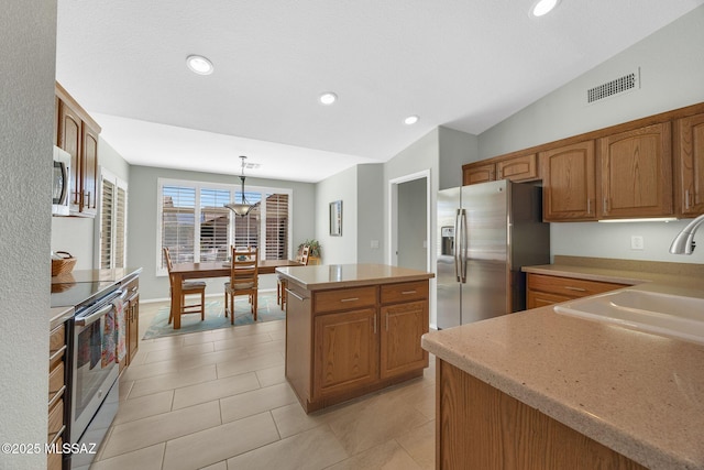 kitchen featuring vaulted ceiling, decorative light fixtures, sink, a center island, and stainless steel appliances