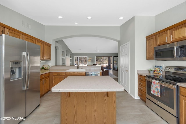 kitchen with sink, light tile patterned floors, stainless steel appliances, a kitchen island, and kitchen peninsula