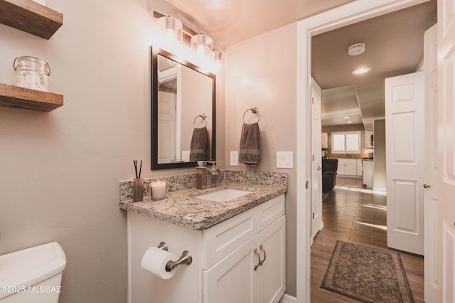 bathroom with hardwood / wood-style flooring, vanity, and toilet