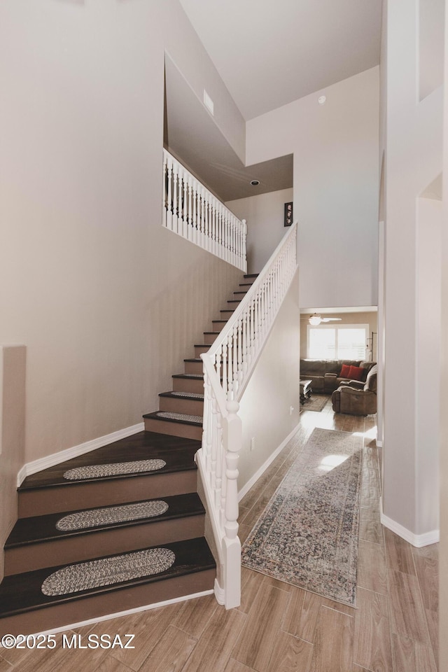 stairs featuring wood-type flooring and a high ceiling