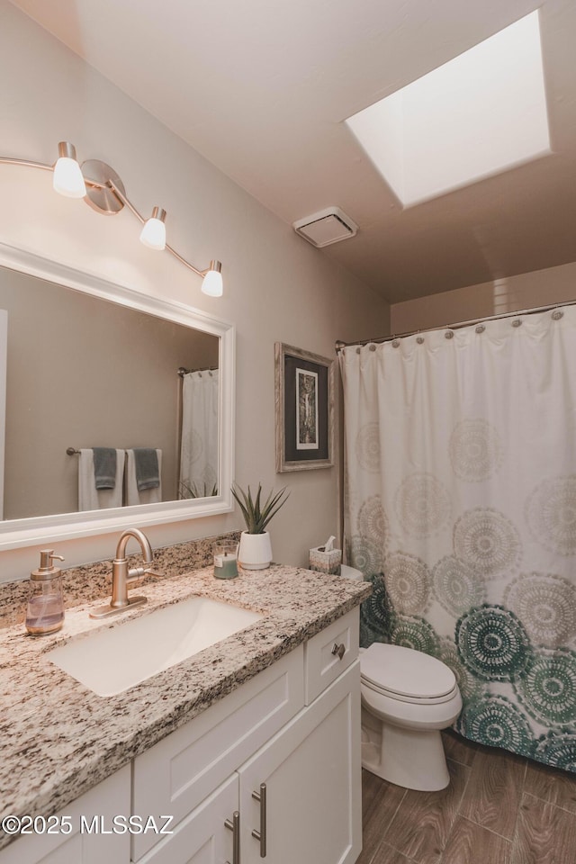 bathroom featuring hardwood / wood-style flooring, vanity, toilet, and a skylight