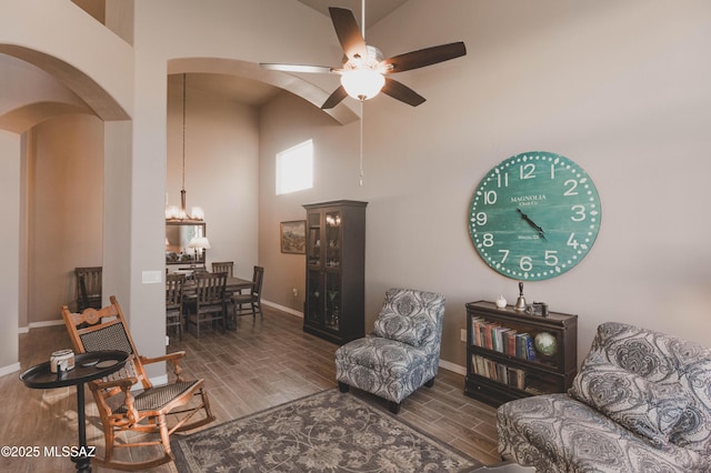 living room featuring a towering ceiling and ceiling fan with notable chandelier