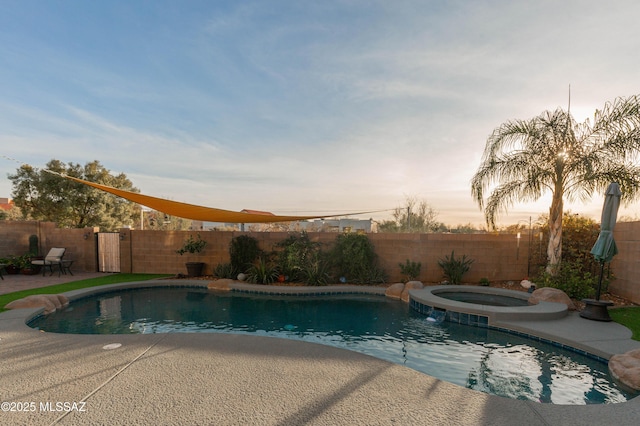 pool at dusk with an in ground hot tub and a patio