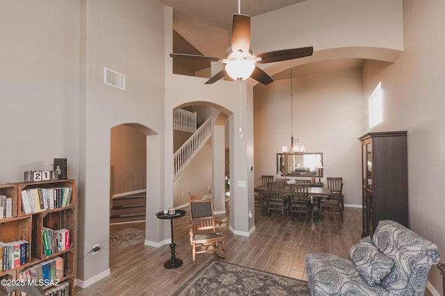 living room with ceiling fan with notable chandelier and a high ceiling