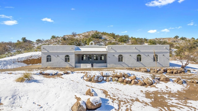 snow covered property with stucco siding