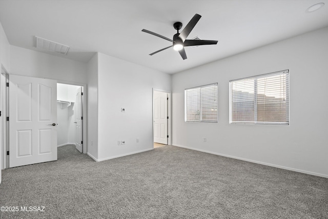 unfurnished bedroom with a walk in closet, ceiling fan, and carpet