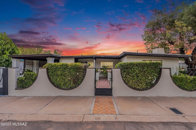 mid-century modern home with a fenced front yard, a gate, and stucco siding