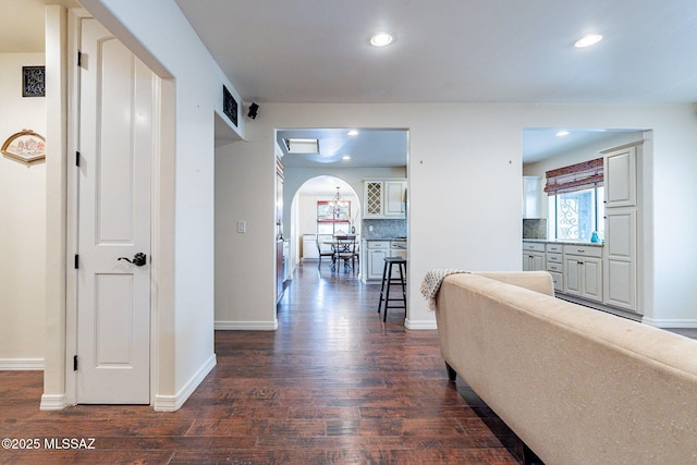 hallway featuring arched walkways, dark wood-type flooring, and recessed lighting