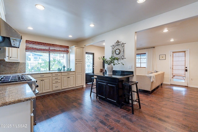 kitchen with recessed lighting, dark wood-style floors, exhaust hood, and a kitchen breakfast bar