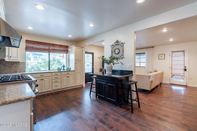 kitchen with range hood, a breakfast bar area, dark wood finished floors, and a center island