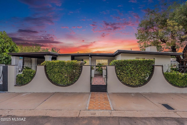 mid-century home featuring stucco siding, a gate, and a fenced front yard