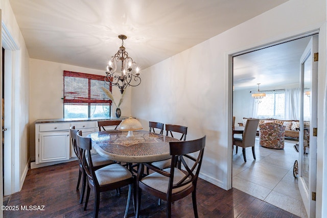 dining room with dark wood finished floors, baseboards, and an inviting chandelier