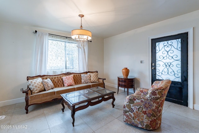 living area with a chandelier, light tile patterned floors, and baseboards