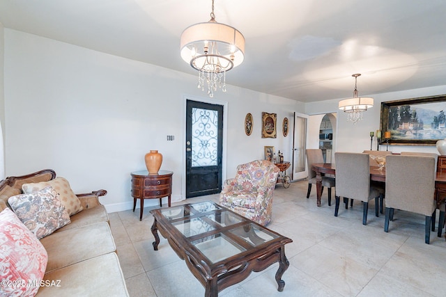 living area featuring light tile patterned flooring, baseboards, arched walkways, and an inviting chandelier
