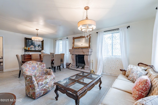 living room with light tile patterned flooring, baseboards, and a fireplace with raised hearth