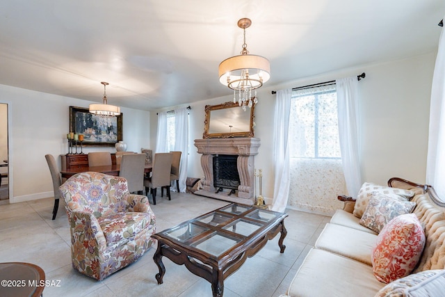 living room featuring a fireplace with raised hearth, a chandelier, and baseboards