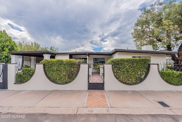 view of front of property with a fenced front yard, a gate, and stucco siding