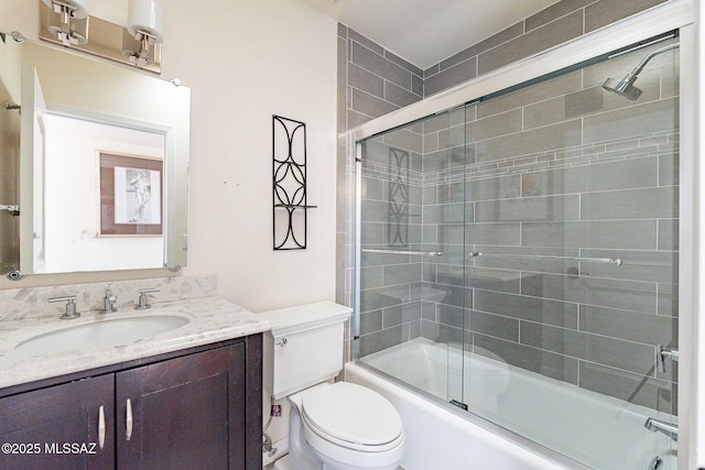 bathroom with combined bath / shower with glass door, toilet, and vanity