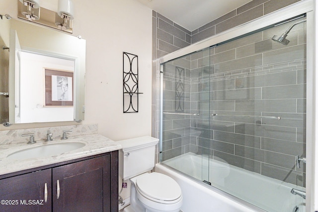 full bathroom featuring toilet, combined bath / shower with glass door, and vanity