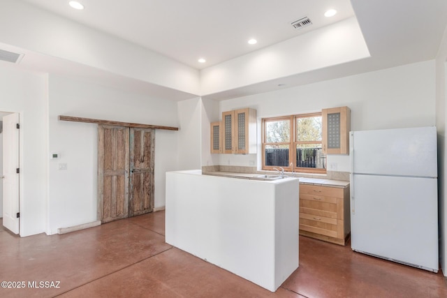kitchen featuring glass insert cabinets, visible vents, light countertops, finished concrete flooring, and freestanding refrigerator