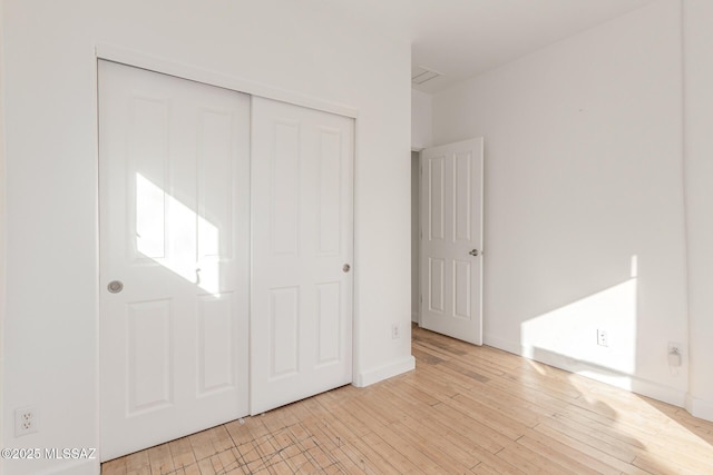 unfurnished bedroom with light hardwood / wood-style flooring and a closet