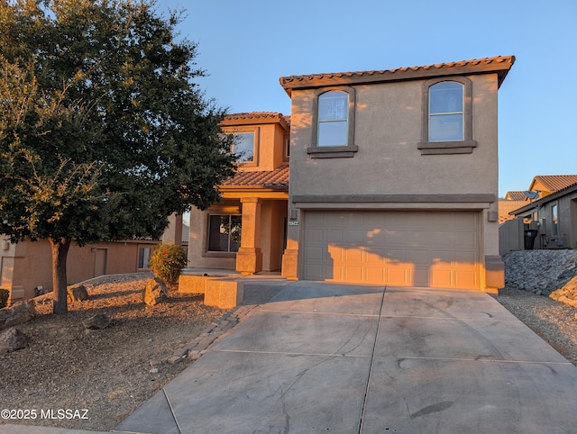 mediterranean / spanish home featuring a tiled roof, a garage, driveway, and stucco siding