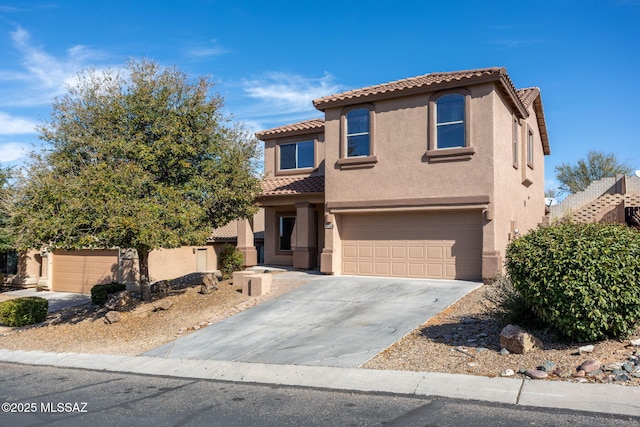 mediterranean / spanish house with a tile roof, an attached garage, driveway, and stucco siding